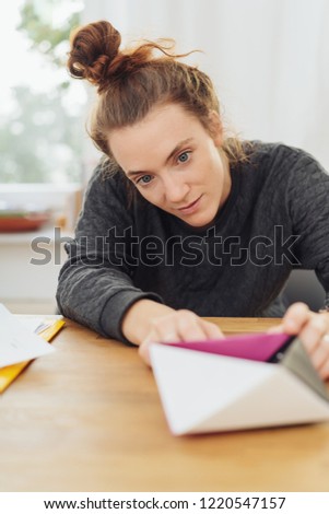 Creative young woman in a design studio leaning forwards to study 3D models on the desk in front of her with an absorbed expression