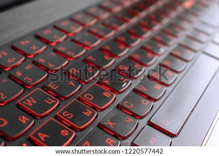 Closeup of gamer laptop keyboard red illumination, backlit keyboard, russian letters.
