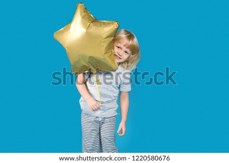 Happy little boy in a pajamas with balloon gold star on a blue background