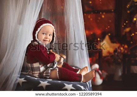 Stylish little toddler boy, playing around christmas decoration at home
