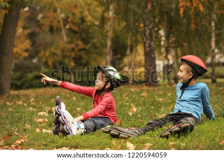 Cute roller skaters sitting on grass in park