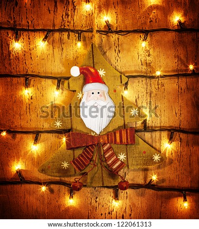 Picture of beautiful Christmastime ornament, little decorative Christmas tree hanging on wooden door adorned xmas lights, grunge glowing background, festive electrical garland, Santa Claus decor