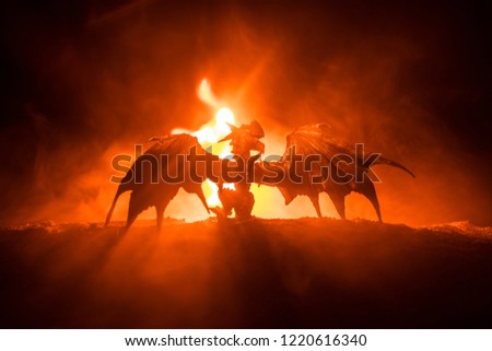 Silhouette of fire breathing dragon with big wings on a dark burning fire background. Selective focus