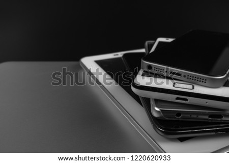 Stack of high-end smartphones on black desk.