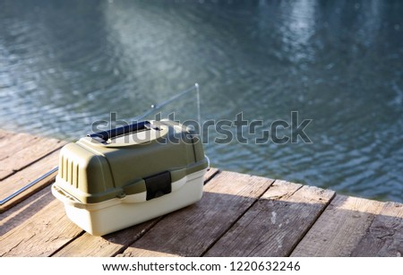 Tackle box and rod for fishing on wooden pier at riverside. Recreational activity Royalty-Free Stock Photo #1220632246
