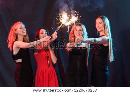 New year party, celebration and holidays concept - group of friends having fun with sparklers