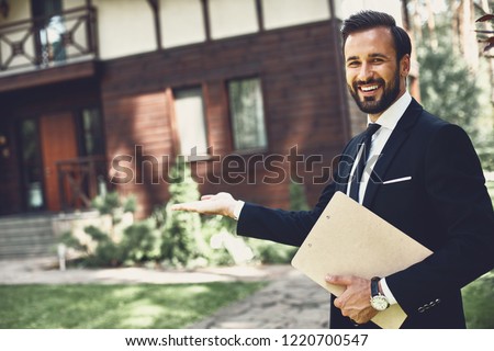 Cheerful professional young realtor looking happy and smiling while demonstrating the house Royalty-Free Stock Photo #1220700547