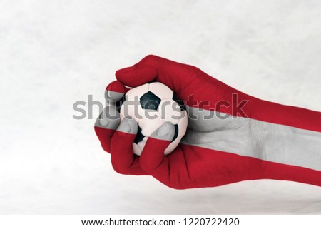 Mini ball of football in Austria flag painted hand on white background. horizontal triband of red (top and bottom) and white. Concept of sport or the game in handle or minor matter.