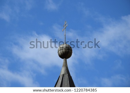tip of the bell tower of a church with clouds in the background
