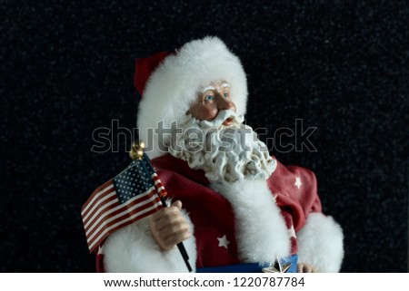 patriotic Santa Claus wearing red white and blue suit holding the American flag on a black background with writing space