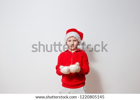 cute seven year old boy in red hoodie and white fluffy mittens on white background