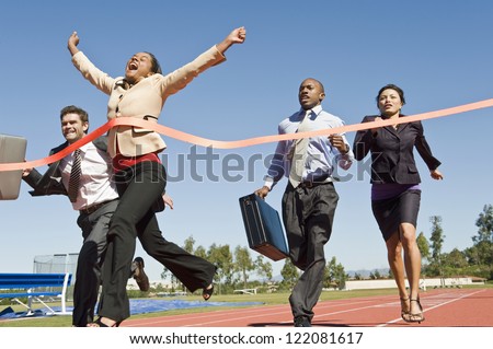 Motion blur shot of a cheerful business woman crossing the finish line with colleagues running in the background Royalty-Free Stock Photo #122081617