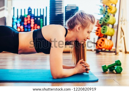 The girl is engaged in fitness and does exercise plank during training. Toned image. concept of a healthy lifestyle and exercise. does exercise plank during training from the side chest view