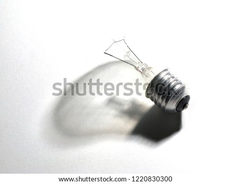 close-up of the filament of a light bulb leaning on a white fabric and bulb-shaped shadow