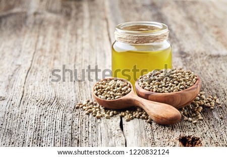 Hemp raw oil and seeds on wooden board Royalty-Free Stock Photo #1220832124