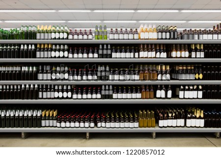 Beer bottles on shelf in supermarket with black and white labels. Suitable for presenting new beer bottles and new designs of labels among many others. Royalty-Free Stock Photo #1220857012