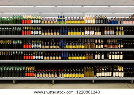 Beer bottles on shelf in supermarket with colorful blanco labels. Suitable for presenting new beer bottles and new designs of labels among many others. Royalty-Free Stock Photo #1220881243