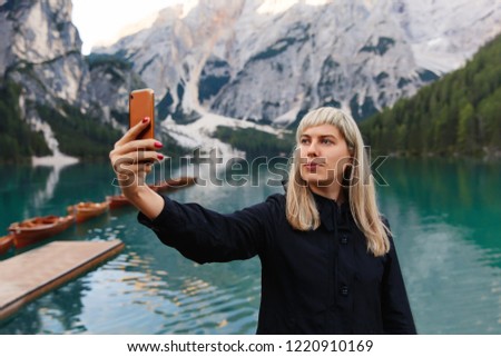 Travel and adventure. Travel hiker makes selfie photo on smartphone on beautiful landscape, Dolomites Mountaines. Braies Lake (Lago di Braies), hiking on alpine lake, Alps, Dolomites, Italy, Europe