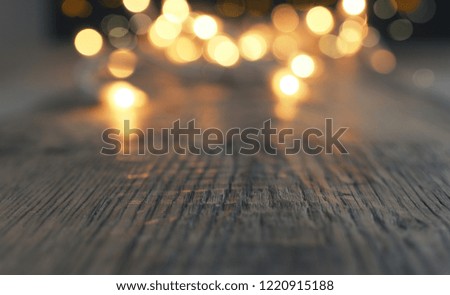 Blurred Christmas lights on a rustic wooden table with space for text or image, selective focus on foreground
