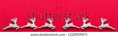Christmas deers on red knit background. Top view with copy space.