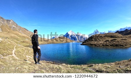 A man traveller relaxing and looking to the peak mountain with blue sky and clouds background at Grindelwald,Swiss.Happy Vacation holiday in beautiful outdoor scene landscape.Travel Freedom concept.
