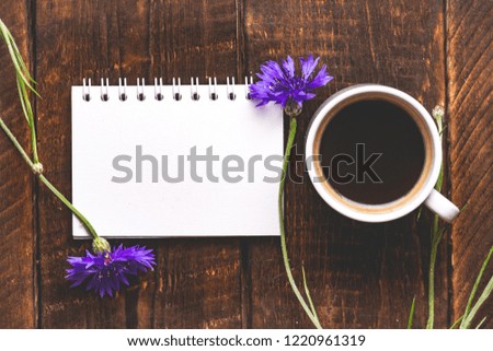 Cup of coffee with cornflowers on a wooden background. Top view. Coffee and flower. Copy space 