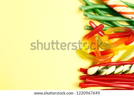 Tasty candies on yellow background. Place for text. Top view, flat lay.