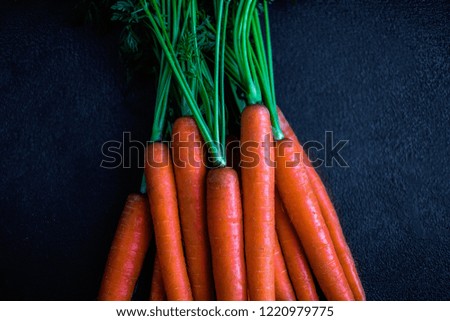  Fresh raw Carrots with stems. Garden Carrots on a black background. Top view