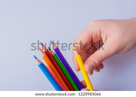 Hand holding color Pencils placed on a white background