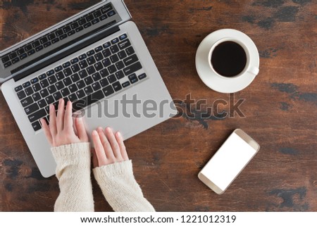 Dark wooden office desk table with laptop computer, mobile phone. Top view and flat lay with copy space, winter background