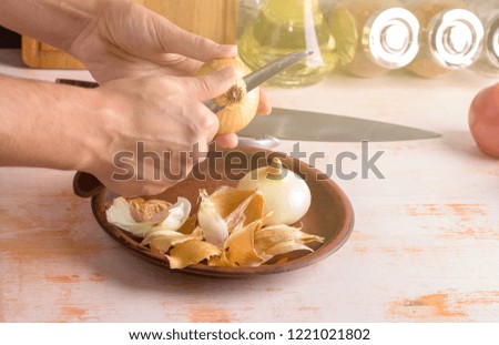 Onion and knife in female hands close-up, cleaning onions. Cooking process. The concept of homemade food. Royalty-Free Stock Photo #1221021802