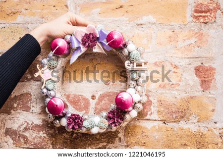 Christmas decoration wreath, accessories deers and candles, golden, pink, white and silver balls, on a brick wall