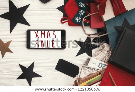 Christmas big sale text, xmas sign on phone screen. Special discount christmas offer. Phone with advertising message at money, wallet, bags, clothes, gift boxes, price tags. Shopping