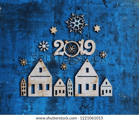 christmas and new year card with tree decorations/wooden figures of houses,snowflakes on the blue rustic background