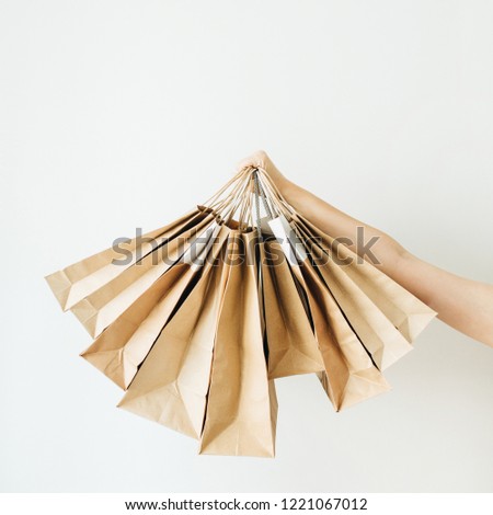 Black Friday sales discount concept. Female hands holding craft paper bags on white background.