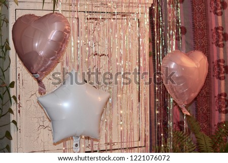 Pink heart and white star party balloons with sparkling streamers and led wire lights in the background at a six year olds birthday party.