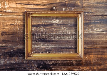 Old vintage gold ornate frame for picture on grunge wooden wall