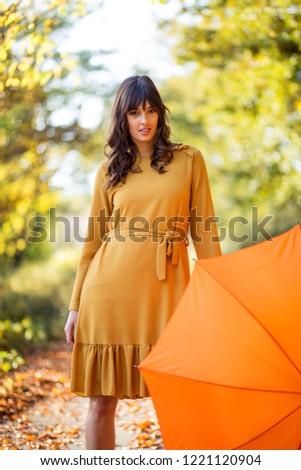 Pretty woman posing with umbrella in a park at autumn day