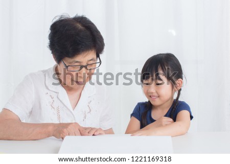 little and old asian reading picture book