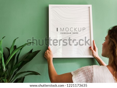Woman hanging a frame mockup on a wall