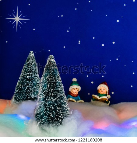 Two carolers practice in the forest under a starry night.