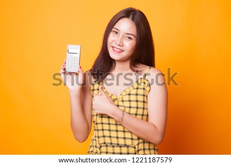 Asian woman thumbs up with calculator on yellow background