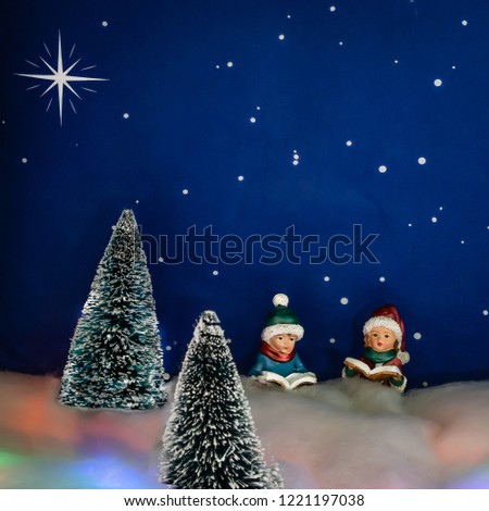 Two carolers practice in the forest under a starry night.