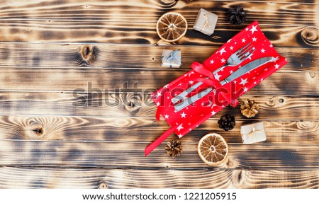 Christmas decoration of cutlery, tableware on red napkin. Composition with cones, dried orange slices, boxes of gift. Flat lay, top view. 