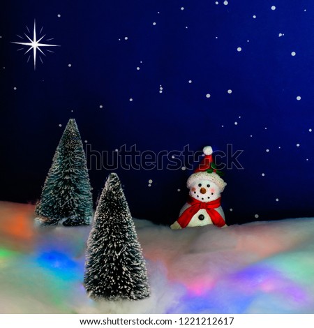 A snowman lsmiles in a forest at night.