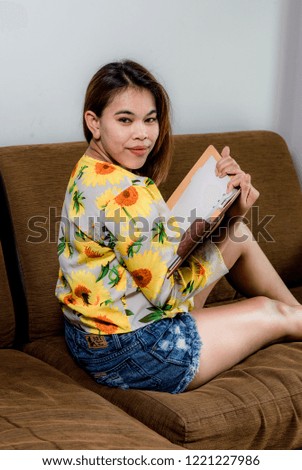 Woman reading a book in a sofa set for summer fashion.