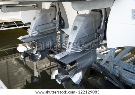 Twin motors suspended from an expensive pleasure boat safely stored on a hyrdolic lift in a dock Royalty-Free Stock Photo #122129083