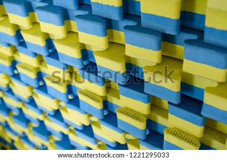 blue-yellow sports mats stacked in large stack