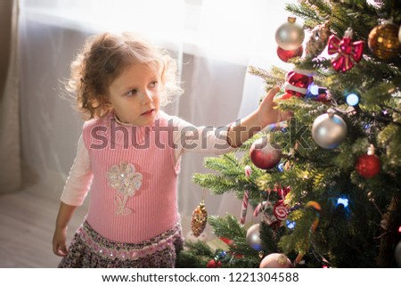 Three-year-old girl in a room with a Christmas tree