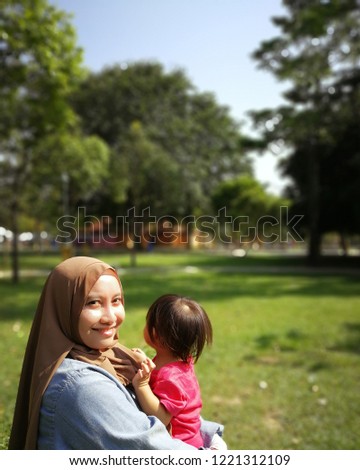muslim mother carrying and playing with her baby girl in the park.